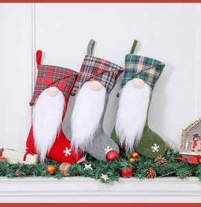 Close-up of three plaid Christmas gnome stockings with snowflake details on a white mantel