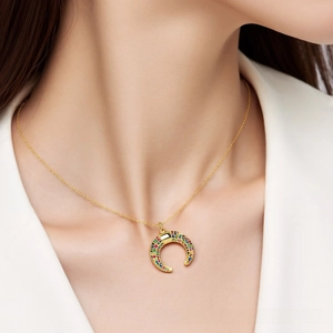 Detail of a gold horn pendant with multicolored micro-pave zircons on a delicate chain