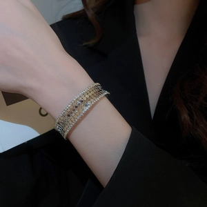 Detail of layered gold metal mesh bracelet with shimmering zircon crystals on a model