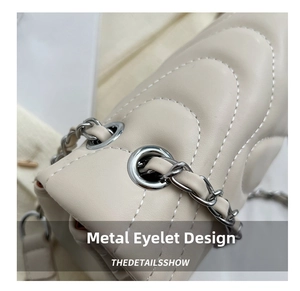 Close-up of quilted V-pattern leather with silver chain through metal eyelets