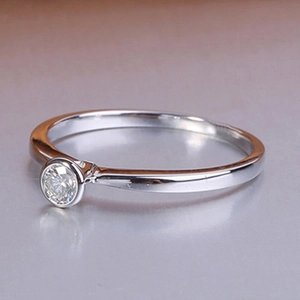 Detail showing high-polished silver ring with bezel-set round crystal on reflective surface