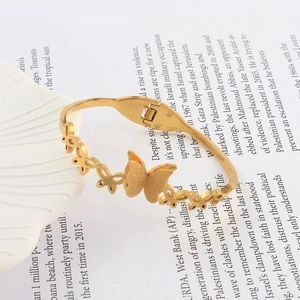 Detail of gold butterfly bangle featuring frosted textures and a spring clasp design