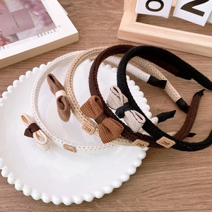 Detailed close-up of four knitted bow headbands in coffee and brown tones on a ceramic plate