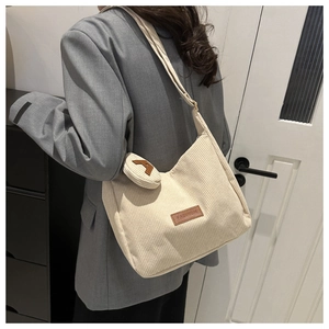 Detail view of beige corduroy tote bag with mini coin purse on a stylish grey blazer