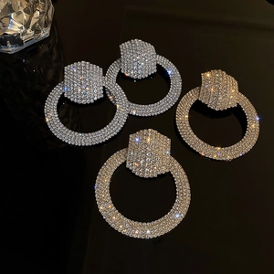 Close-up of sparkling hexagonal and round crystal hoop earrings in silver and gold finish