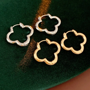 Close-up of gold and silver clover hoop earrings on green velvet background