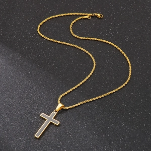 Macro detail of golden cross pendant with black enamel inlay on twisted rope chain necklace