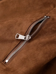Detailed macro view of silver metal zipper on premium brown suede jacket fabric