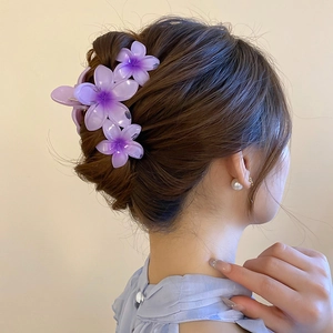 Detailed view of three purple acrylic flower hair claws on a stylish updo hairstyle