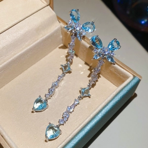 Detail of silver tassel earrings with blue zircon heart and butterfly on a jewelry box