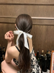 Rear view of a floral silk hair ribbon tied elegantly on a low ponytail hairstyle
