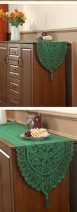 Close-up of green lace table runner with fringe on a wooden cabinet in a cozy room