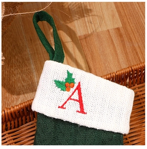 Close-up of green cable-knit Christmas stocking with embroidered letter A in a basket