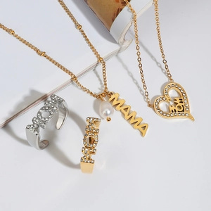 Detail view of gold and silver MOM rings and MAMA necklaces with heart and pearl charms