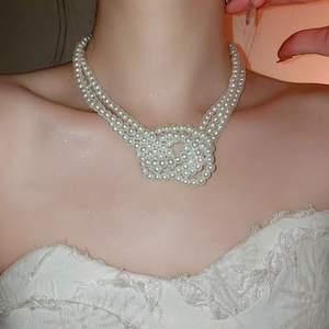 Detailed close-up of triple-strand knotted pearl necklace on model with elegant luster