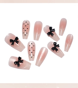 Macro detail of pink gradient coffin press-on nails with black bows and polka dots