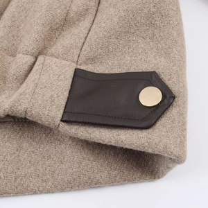 Détail d'une veste en laine avoine avec bordure en cuir brun et boutons dorés