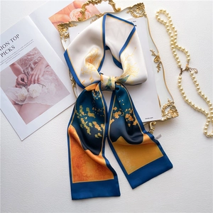Blue and orange silk-like twilly scarf with floral patterns on a vintage gold tray