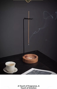 Detail of minimalist hanging incense burner with wooden base and smoke rising