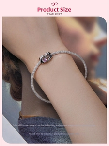 Detail of S925 sterling silver mesh bracelet with pink heart gemstone pendant on wrist
