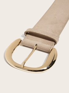 Macro shot of beige suede belt with a large gold metal horseshoe buckle detail