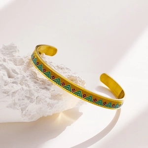 Detailed close-up of a gold open cuff bracelet with colorful geometric triangle patterns