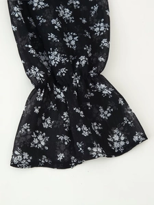 Detailansicht der elastischen Rüschenmanschetten an einem schwarzen floralen Chiffonkleid