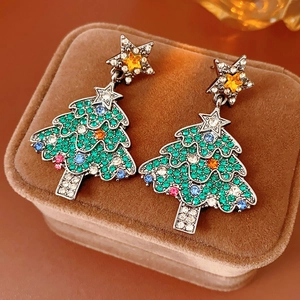 Macro shot of silver vintage Christmas tree earrings with colorful rhinestones on velvet