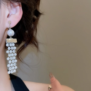 Detailed view of silver clip-on earrings featuring large pearls and elegant beaded tassels