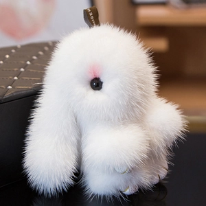 White mink fur bunny keychain with golden paws hanging on a black quilted leather bag