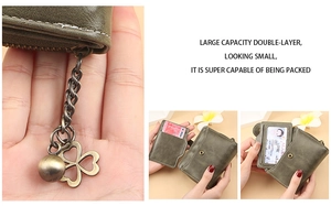 Detail of green leather wallet showing metal zipper and four-leaf clover pendant charms