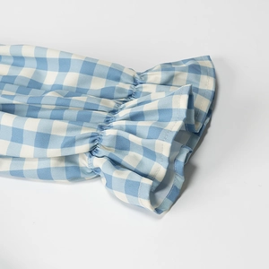 Detail of blue and white plaid shirt showing ruffled elastic cuffs and fabric texture