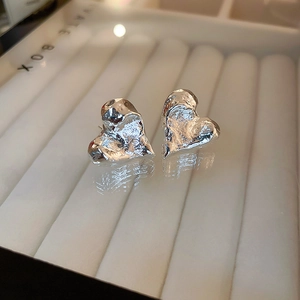 Macro shot of silver heart studs with unique lava texture on a white display box