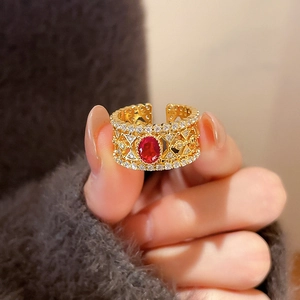 Macro shot of a vintage gold floral ring with a red oval gem and white zircons