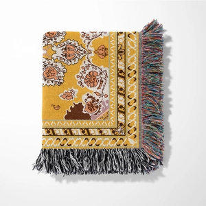 Close-up of yellow Bohemian woven throw blanket showing intricate floral pattern and fringe