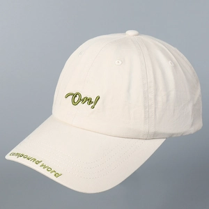 Detalle de gorra de béisbol crema con bordado verde en relieve.