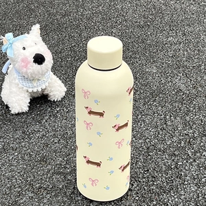 Vue détaillée d'une bouteille isotherme crème avec motifs de teckels et nœuds roses
