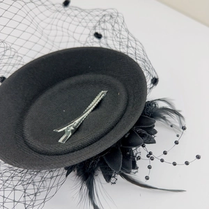 Detail of black vintage fascinator showing the metal clip, mesh veil, and feather