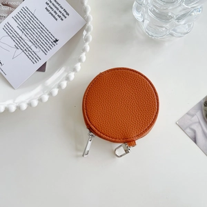 Detail of round orange lychee leather coin purse with silver zipper and metal hook