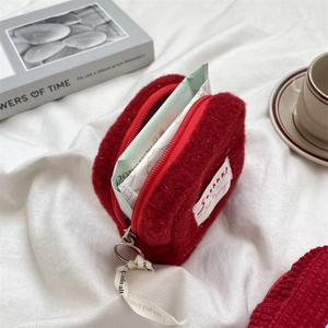 Macro shot of red plush sanitary pouch on soft fabric with zipper and side label