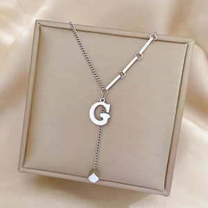 Detail of silver G-letter pendant on punk style stainless steel chain in a jewelry box