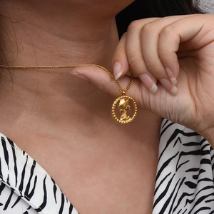 Classic gold portrait coin relief pendant necklace with thin chain on a model