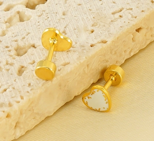 Detailed macro view of heart shaped gold stud earring with gold leaf white enamel detail