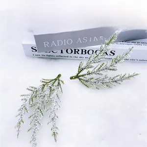 Detail of two frosted artificial pine branches with snow effect on white plush background