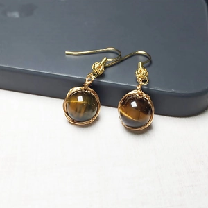 Détail de boucles d'oreilles faites main en or 14K avec pierre œil de tigre ronde marron