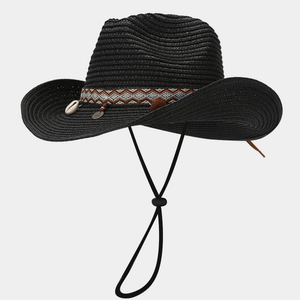 Dettaglio cappello da cowboy in paglia nera con fascia etnica e ciondoli di conchiglie