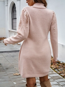 Détail d'une robe en maille rose avec des ornements en perles sur les manches bouffantes
