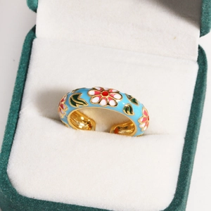 Macro detail of sky blue enamel flower ring with colorful petals in a jewelry box