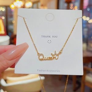 Close-up of golden Queen letter pendant with crown and shimmering zircon accents