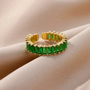 Macro detail of adjustable gold ring with emerald-cut green zircons on satin